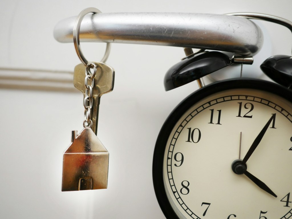 House key on a keychain hanging from an alarm clock